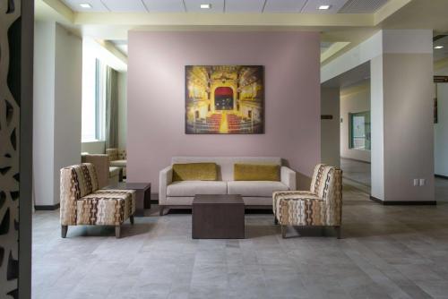 萨卡特卡斯萨卡特卡斯汉普顿酒店的大堂配有沙发和两把椅子,画作