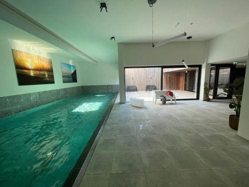 卡德赞德Design Apartment with 60m² terrace - heated inside pool and wellness facilities - very close to the beach的游泳池,位于带客厅的房屋内