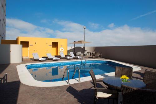 锡劳汉普顿希尔顿思劳阿罗普墨西哥酒店的一座带椅子和桌子的游泳池位于大楼旁