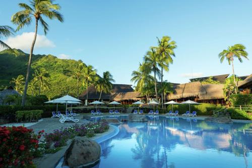 帕佩托艾Hilton Moorea Lagoon Resort & Spa的度假村的游泳池配有椅子和遮阳伞