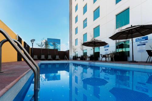 莱昂莱昂汉普顿酒店的一座带椅子和遮阳伞的游泳池位于一座建筑旁边