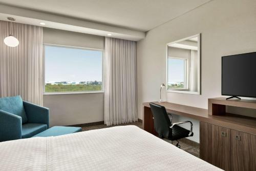 蒙特雷Hampton Inn By Hilton Monterrey Apodaca的酒店客房配有一张床、一张书桌和一台电视。