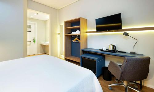 瓜鲁柳斯Hampton by Hilton Guarulhos Airport的配有一张床和一张书桌的酒店客房