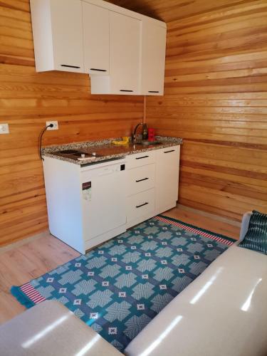 凯麦尔Arlin Bungalows的厨房配有白色橱柜和蓝色地毯。