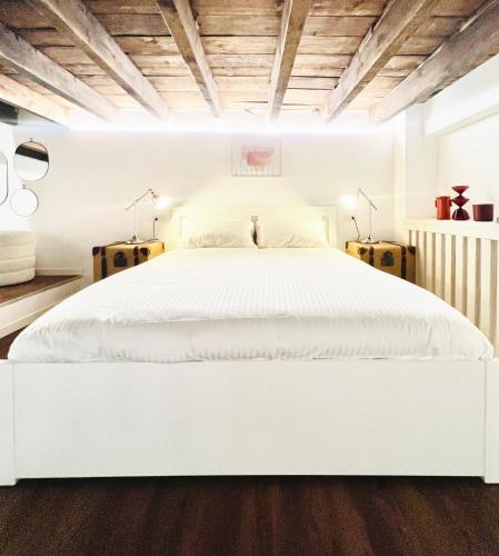 米兰Tarra Luxury Suite的白色卧室内的白色床,设有木制天花板