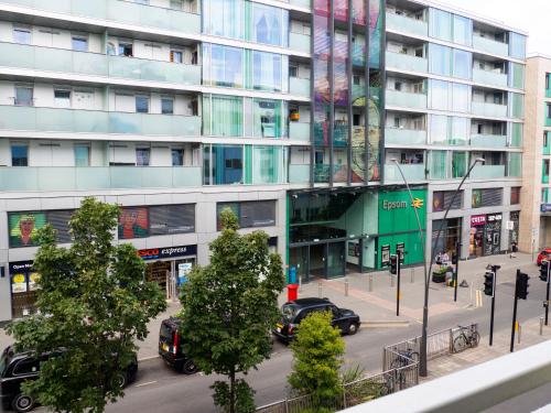 埃普瑟姆Stylish 2 bedroom apartment in the heart of Epsom town centre的一条城市街道,汽车停在高楼前