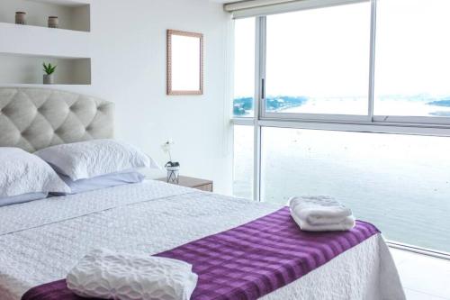 瓜亚基尔Suite 806 extraordinaria vista al rio con piscina.的一间卧室配有一张床铺,床上铺有紫色毯子
