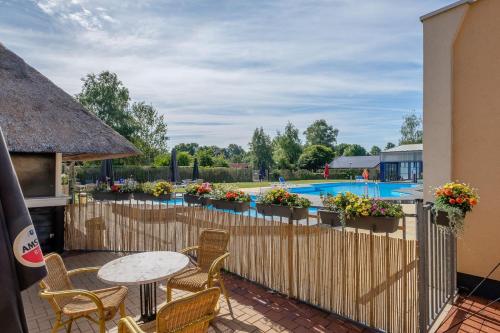 GramsbergenHet Familie Boshuisje - vakantiewoning op prachtig park met veel faciliteiten inc ligbad的一个带桌椅的庭院和一个带游泳池的围栏