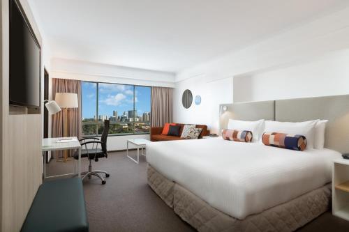 悉尼帕拉马塔莱吉斯酒店的酒店客房设有一张大床和一张书桌。