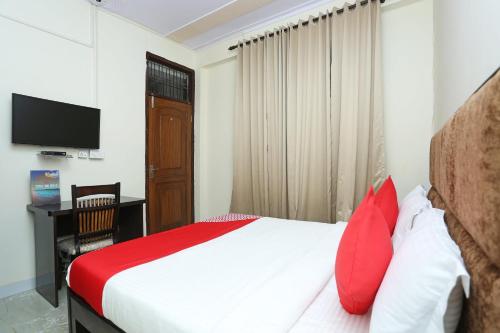 古尔冈OYO Hotel Awesome Villa Near Appu Ghar的一间卧室配有一张带红色枕头的床和电视。