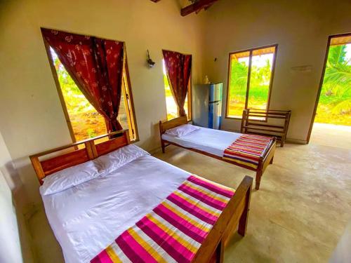 GalewelaNelumgala Cottage -Village Experience的带2扇窗户的客房内的2张床