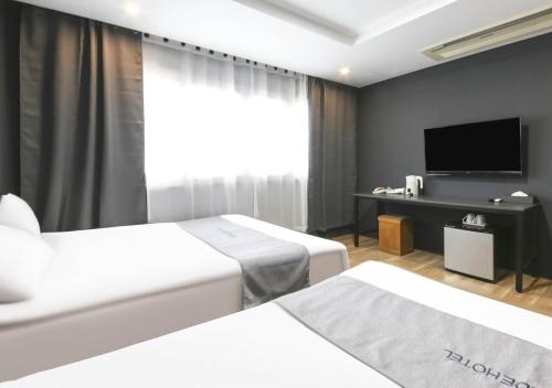 济州市济州公园畔旅游酒店的酒店客房设有两张床和一台平面电视。