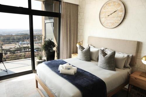 比勒陀利亚Menlyn Trilogy - 2 Bedroom & Great Views - No Loadshedding的卧室配有一张大床,墙上挂着时钟
