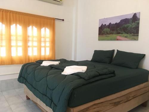 他曲Bamboo Hostel的一间卧室配有一张带绿色床单的床和一扇窗户。