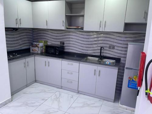 伊凯贾Thistle Greens Apartment的厨房配有白色橱柜和水槽