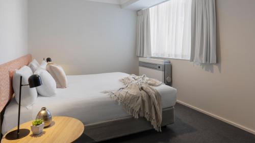 珀斯Oaks Perth Hotel的一间卧室配有一张床、一张桌子和一个窗户。
