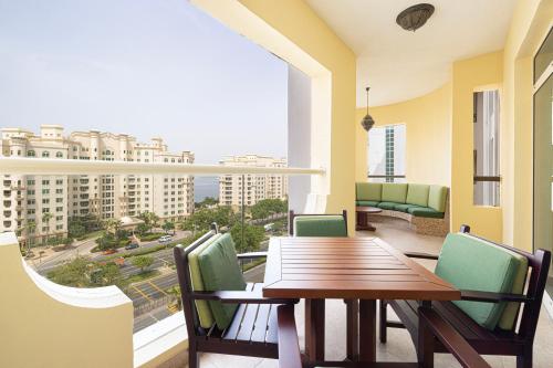 迪拜Royal Club By RVHR, Palm Jumeirah的阳台配有木桌、椅子和大窗户。