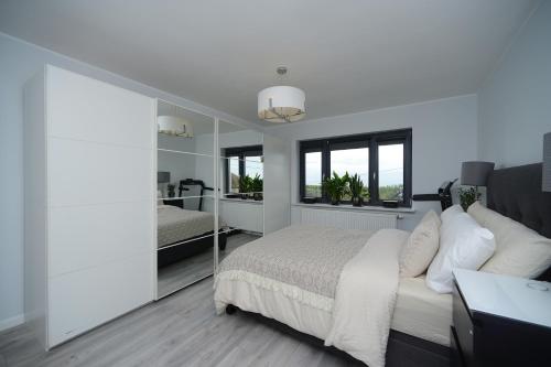FalmerBrighton Seaside Retreat的白色卧室配有床和镜子