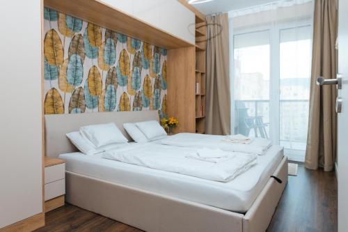 布达佩斯WaterFront City Apartments by UrbanRent的卧室设有白色的床和大窗户