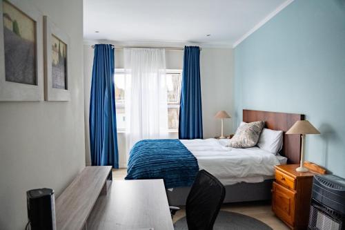 约翰内斯堡3 on Tessa Guesthouse的一间卧室配有床和蓝色窗帘的窗户