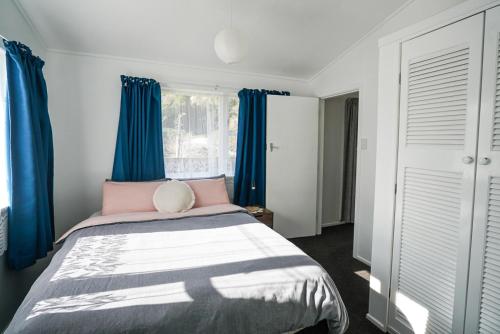 惠灵顿The Hidden Gem - tranquility close to town的一间卧室配有蓝色窗帘和一张大床