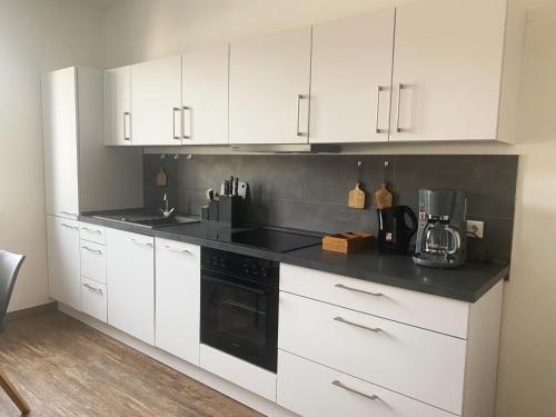 比勒费尔德Loft Appartement的厨房配有白色橱柜和黑炉灶烤箱。