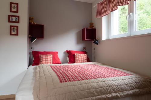 Rimbach-près-MasevauxA l Orée du Bois的一间卧室配有一张带红色枕头的床和两个窗户。