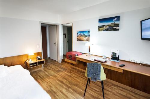 比尔City Hotel Biel Bienne Free Parking的酒店客房配有书桌、床、床和椅子。