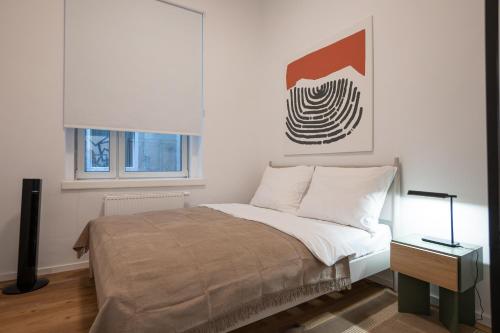 维也纳46 m2 central bright apartment with a balcony的卧室配有一张床,墙上挂着一幅画