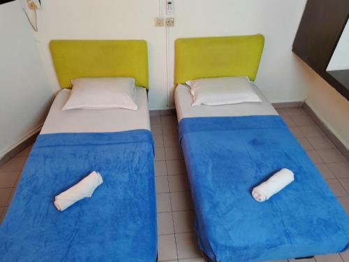 哥打巴鲁Hotel Kenangan的配有两张床铺的蓝色床单和绿色椅子