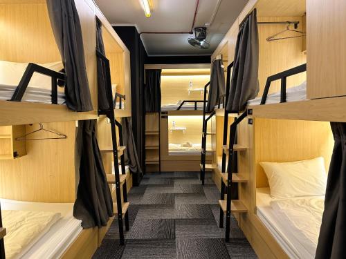 新加坡THE ROOM Capsule Hotel的宿舍间的走廊,配有双层床