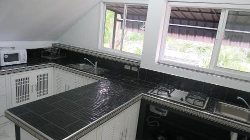 查龙Villa Nap Dau Crown - 8 Br Private Pool Villa - Chalong的厨房配有黑色台面和2扇窗户