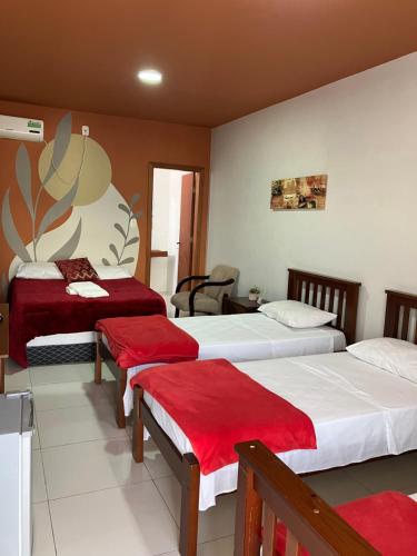 圣加布里埃尔Hotel Zona Sul的酒店客房,配有两张带红色床单的床
