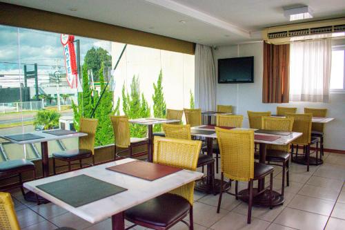 库里提巴巴厘归公园酒店的餐厅设有桌椅和大窗户。