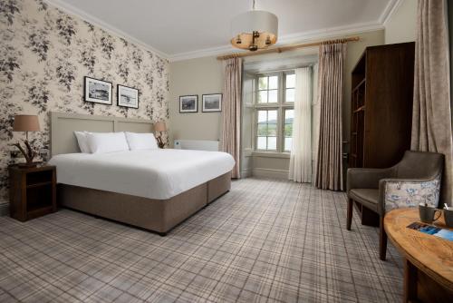 安布尔塞德The Waterhead Inn- The Inn Collection Group的配有一张床和一把椅子的酒店客房