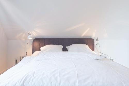 胡苏姆Vis à vis zum Schloss的白色的床、白色床单和枕头