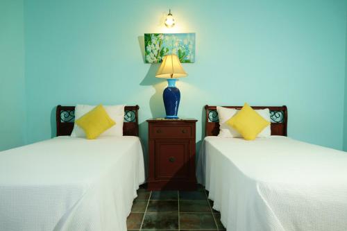 Freemans兰波林假日公寓的一间设有两张带白色床单和灯的床的房间