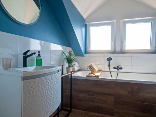 BizeljskoHoliday house Zarja - with sauna and hot tub的带浴缸和水槽的浴室以及2扇窗户。