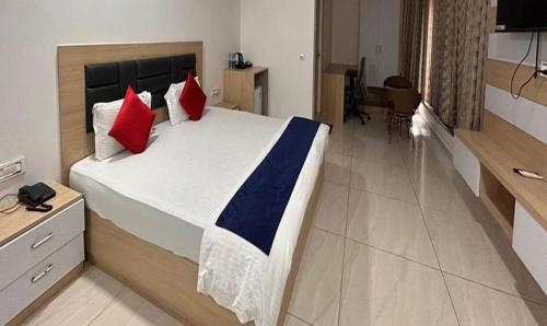 海得拉巴FabHotel Prime Anika Suites的一间卧室配有一张带红色和蓝色枕头的大床