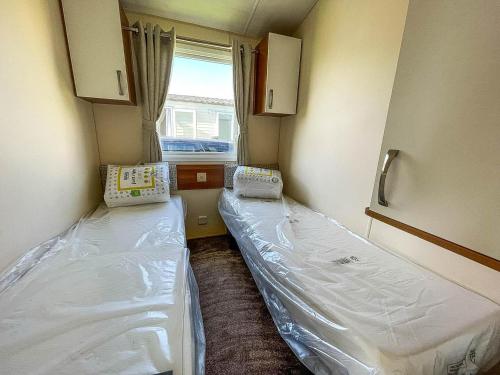 大雅茅斯8 Berth Caravan With Decking At California Cliffs Near Scratby Beach Ref 50019f的小房间设有两张床和窗户