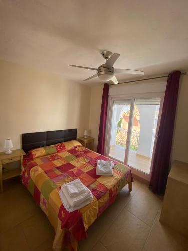 萨阿拉德洛斯阿图内斯La Tahona 27-H的一间卧室配有一张带吊扇和窗户的床。