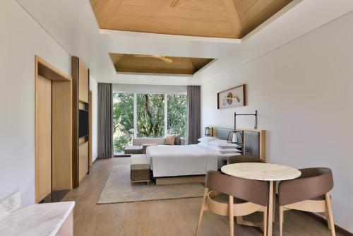 马迪凯里Coorg Marriott Resort & Spa的卧室配有一张床和一张桌子及椅子