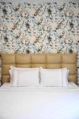 弗尔尼亚奇卡矿泉镇Apartman Ljubica的一张带白色枕头和花卉壁纸的床