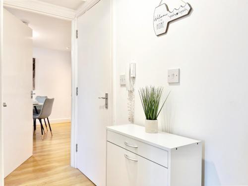 伦敦2 Modern Double Bed Apartment for 6 Guests By Hofin Stays Short Lets & Serviced Accommodation的白色的厨房,配有橱柜和墙上的时钟