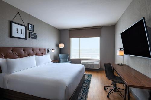 沃思堡Four Points by Sheraton Fort Worth North的酒店客房配有一张床、一张书桌和一台电视。