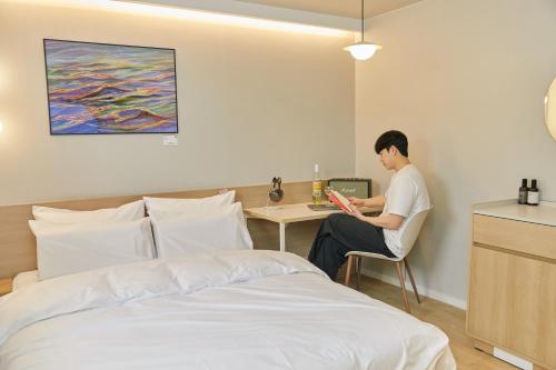 仁川市Aank Thepeak Hotel Incheon Songdo的坐在床边桌子上的人