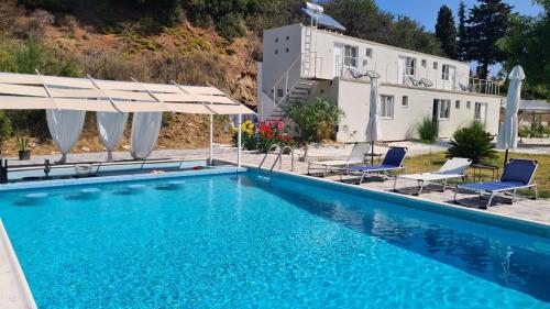 尼尔斯吉尼Greco Paradise Suites - ADULT ONLY的房屋前的带椅子和遮阳伞的游泳池