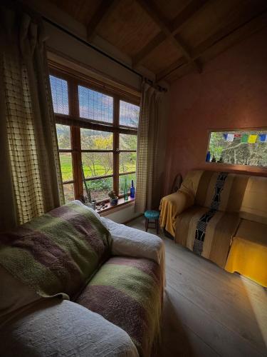 拉纳尔韦湖Cabaña frente al Lago Lanalhue的一间卧室配有一张床、一张沙发和一个窗口