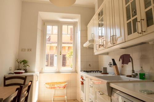 罗马Luxury Borghese Magnolia Suite的厨房配有白色橱柜、水槽和窗户。