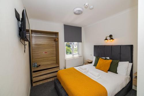 伦敦Woodford Hotel的一间卧室配有一张大床和电视